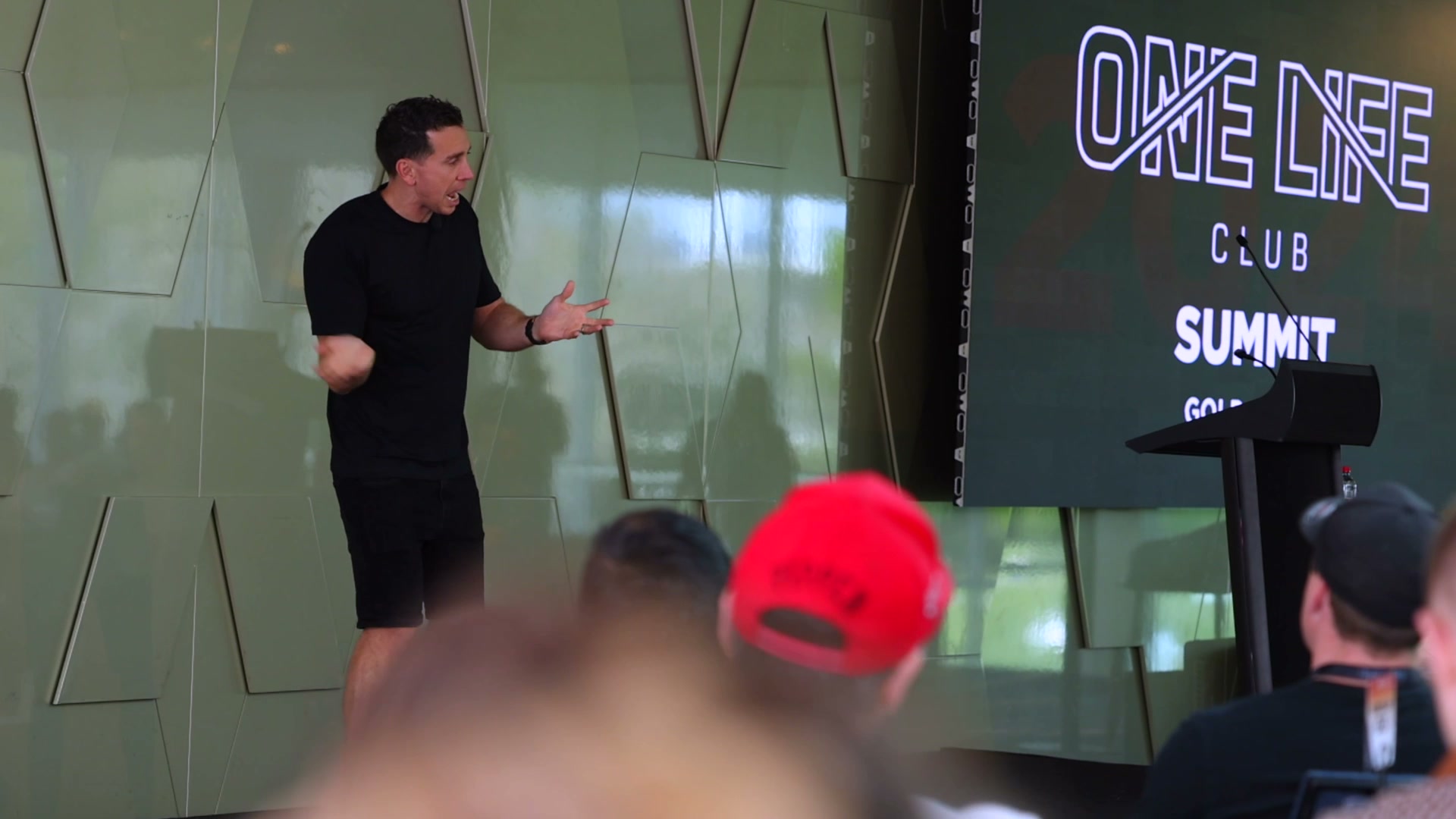 A speaker on stage at a One Life Club summit